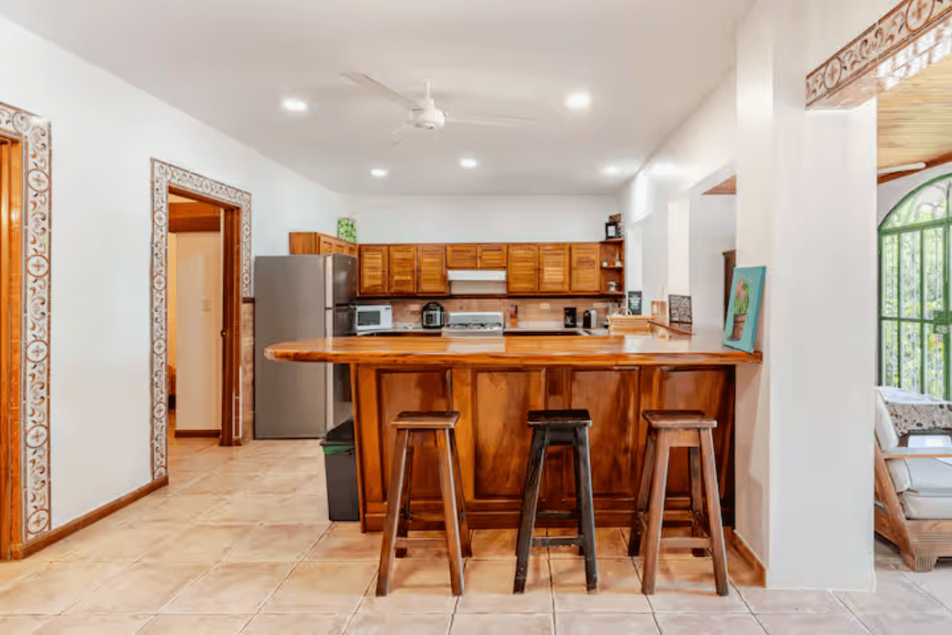A warm, practical kitchen featuring solid wood cabinets, a full stove, microwave, blender, coffee maker, and everything guests need for long or short stays.