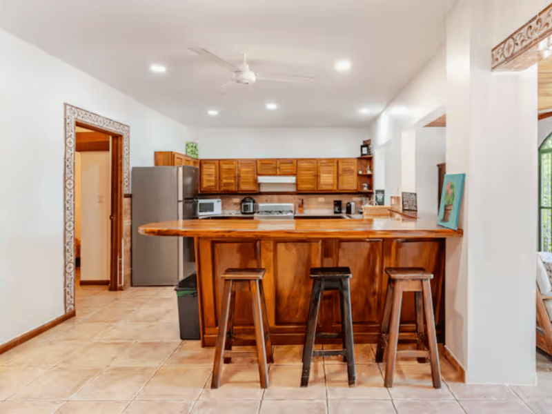 A warm, practical kitchen featuring solid wood cabinets, a full stove, microwave, blender, coffee maker, and everything guests need for long or short stays.
