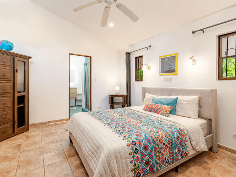 Bright and inviting bedroom with a queen bed, wooden accents, and serene jungle views, offering the perfect balance of comfort and character.